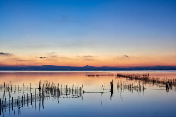 Sonnenuntergang über dem Albufera-See in Valencia mit traditionellen hölzernen Angelruten